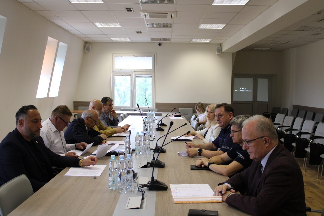 Uczestnicy posiedzenia Komisji Bezpieczeństwa i Porządku siedzą przy dużym stole konferencyjnym w sali Starostwa Powiatowego. Wśród obecnych są przedstawiciele służb mundurowych, instytucji publicznych oraz władz lokalnych. Na czele stołu znajduje się Starosta Tomaszowski Henryk Karwan, prowadzący obrady.