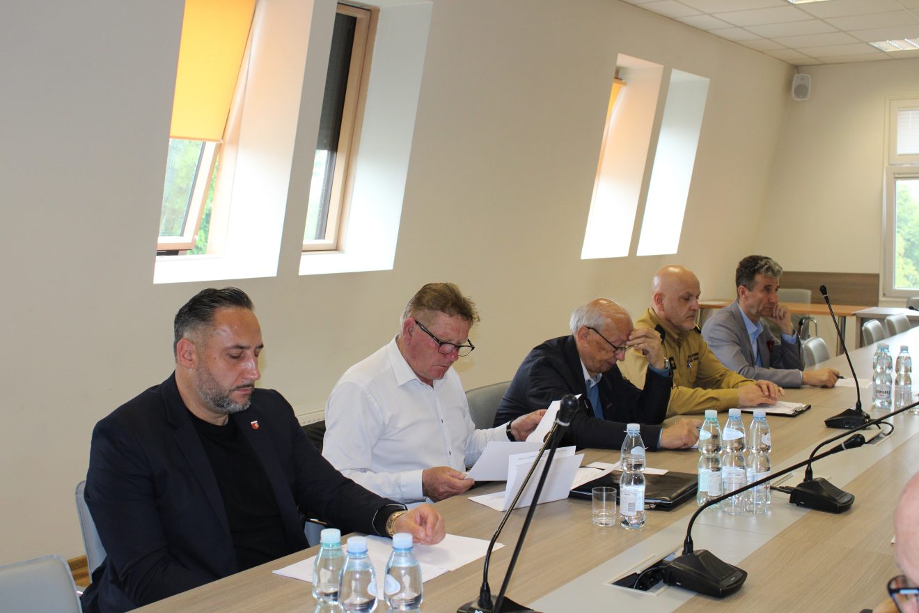 Uczestnicy posiedzenia Komisji Bezpieczeństwa i Porządku siedzą przy dużym stole konferencyjnym w sali Starostwa Powiatowego. Wśród obecnych są przedstawiciele służb mundurowych, instytucji publicznych oraz władz lokalnych.