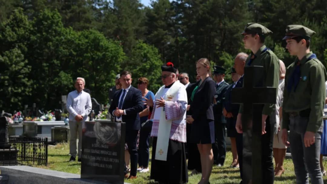 Uczestnicy uroczystości, w tym duchowny, harcerze i przedstawiciele władz, modlą się przy zbiorowej mogile ofiar zbrodni UPA na cmentarzu w Bełżcu