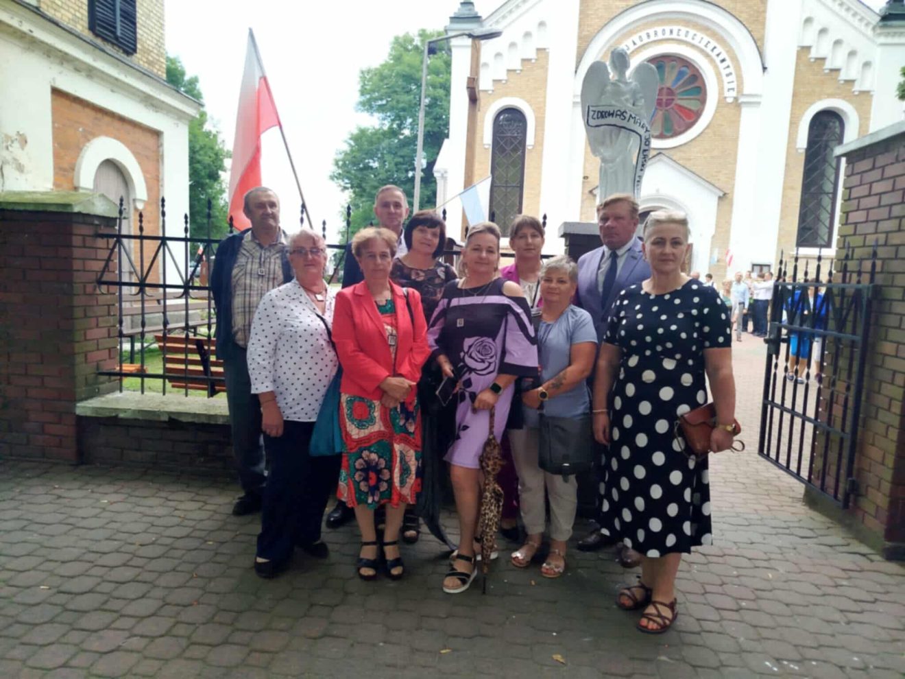 Uczestnicy wydarzenia stoją przed kościołem, pozując do zdjęcia.