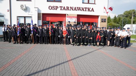 Strażacy pozujący do zdjęcia na tle budynku OSP Tarnawatka