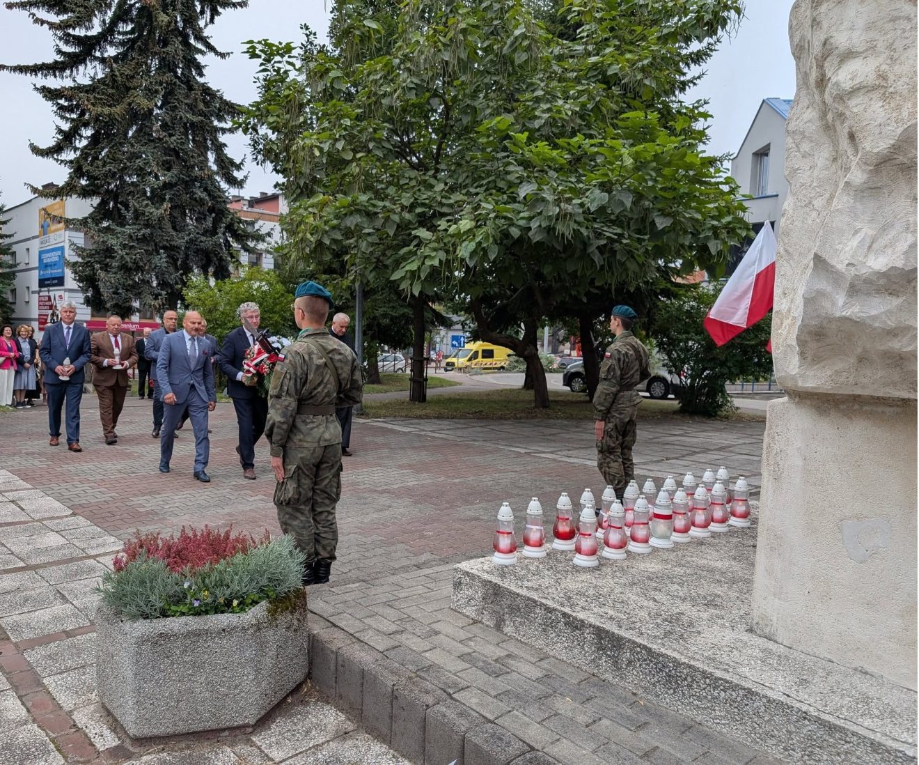 Wicestarosta Jarosław Korzeń idzie pod pomnik „Żołnierzom Września 1939 r.” razem z innym uczestnikiem, który niesie wieniec. Przed pomnikiem stoi warta honorowa, a na ziemi widać złożone znicze.