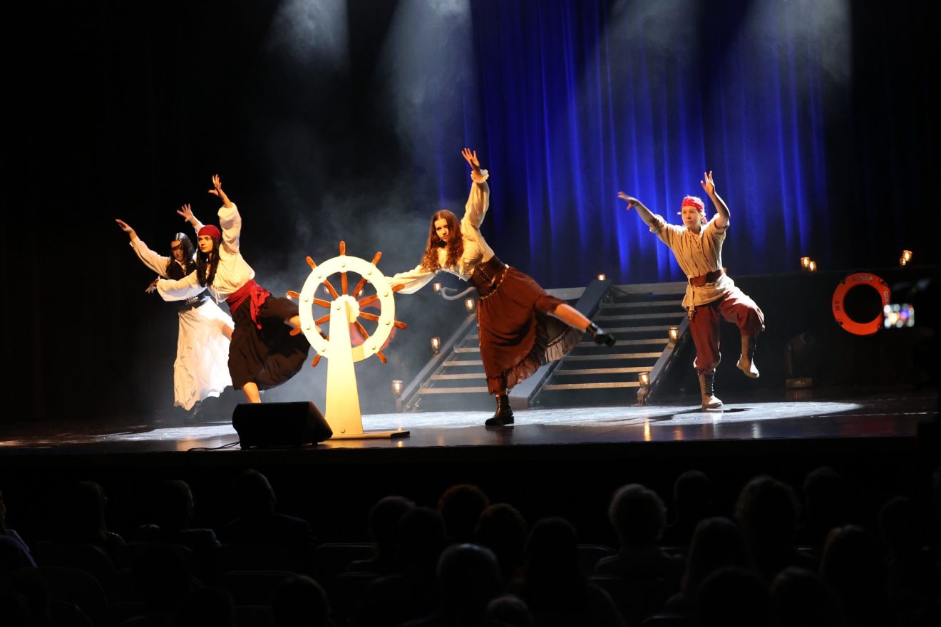 Na scenie członkowie Tomaszowskiego Zespołu Teatralnego występują w strojach piratów, stojąc obok dużego statkowego steru.