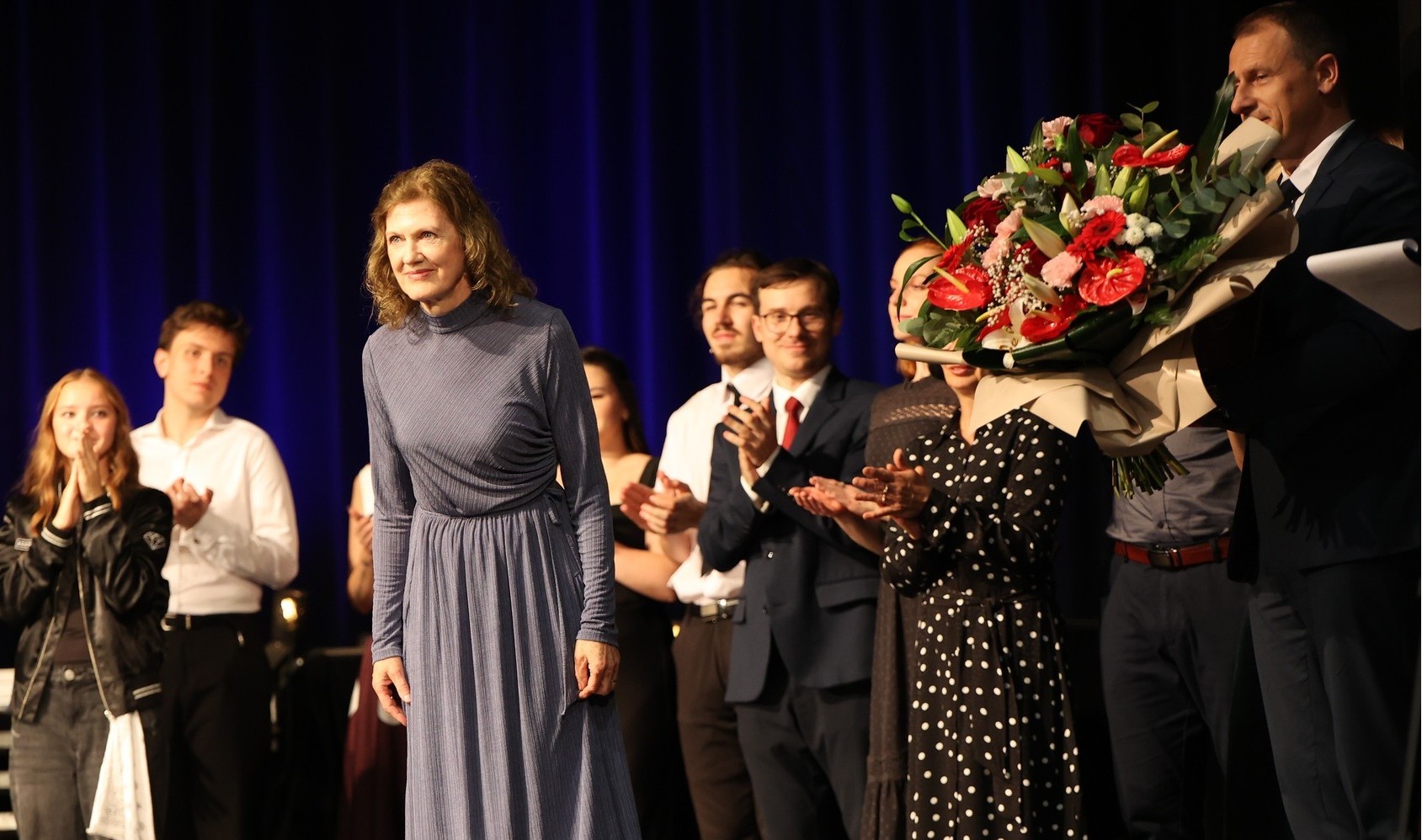 Na scenie stoją członkowie Tomaszowskiego Zespołu Teatralnego, obok nich przewodniczący Rady Powiatu Tomaszowskiego Witold Pitura trzymający bukiet kwiatów