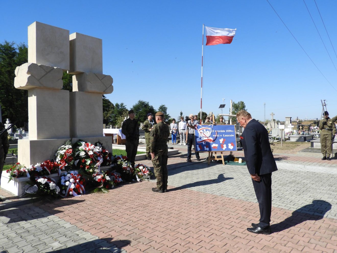 Wiesław Cielica pochyla głowę w zadumie przed pomnikiem na cmentarzu w Łaszczowie, oddając hołd poległym żołnierzom