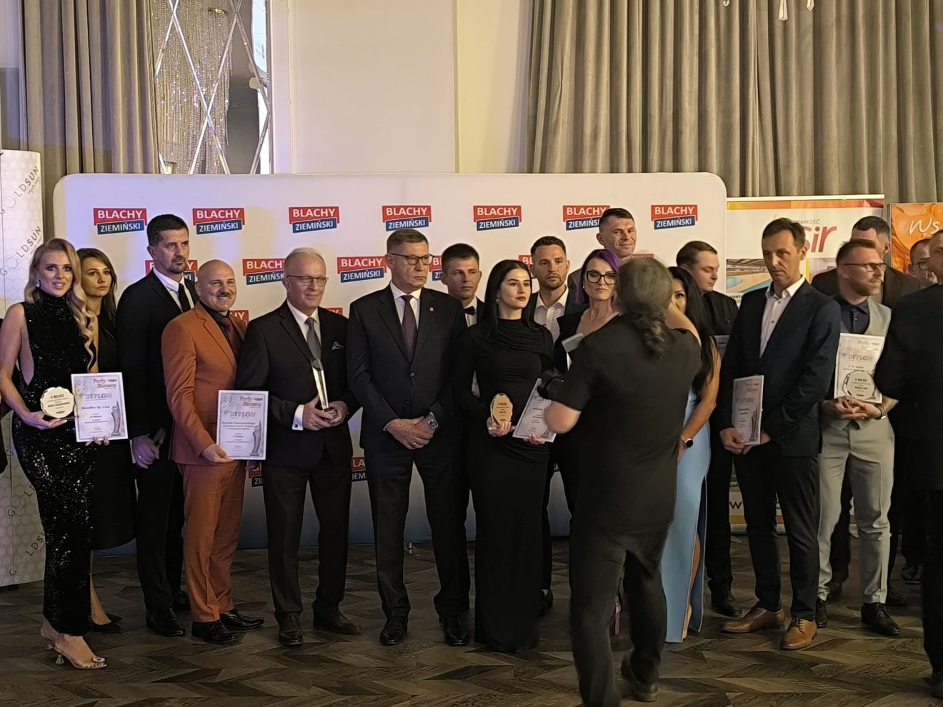 Nagrodzeni pozują do zdjęcia ze statuetką i dyplomem podczas gali Perły Biznesu 2025
