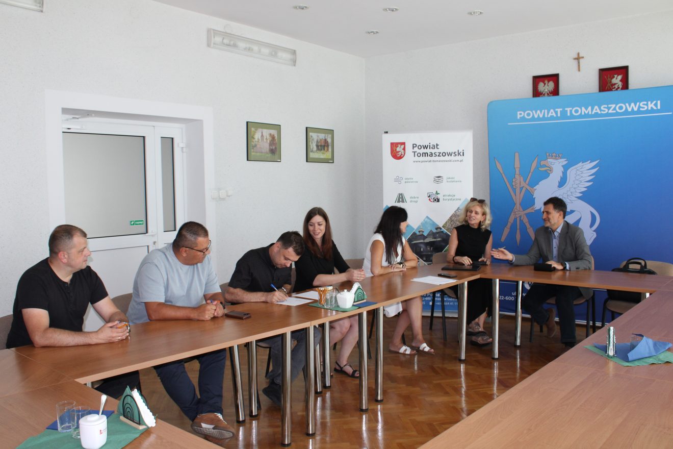 Uczestnicy spotkania podczas rozmowy przy stole z dokumentami projektowymi