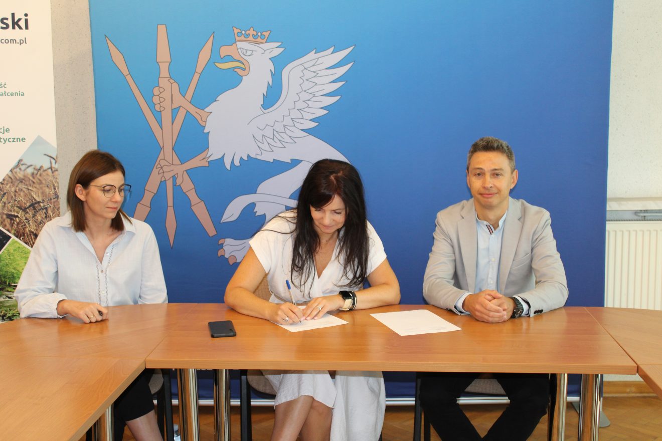 Członkowie komisji odbioru podczas podpisywania protokołu w siedzibie Starostwa Powiatowego w Tomaszowie Lubelskim, w tle ścianka promocyjna powiatu