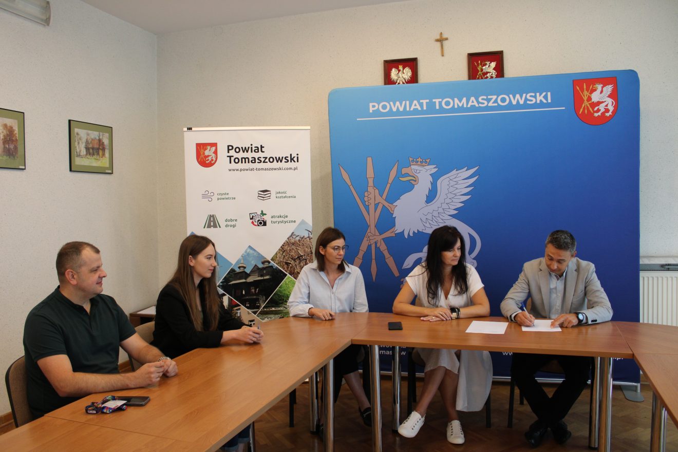 Członkowie komisji odbioru podczas podpisywania protokołu w siedzibie Starostwa Powiatowego w Tomaszowie Lubelskim, w tle ścianka promocyjna powiatu