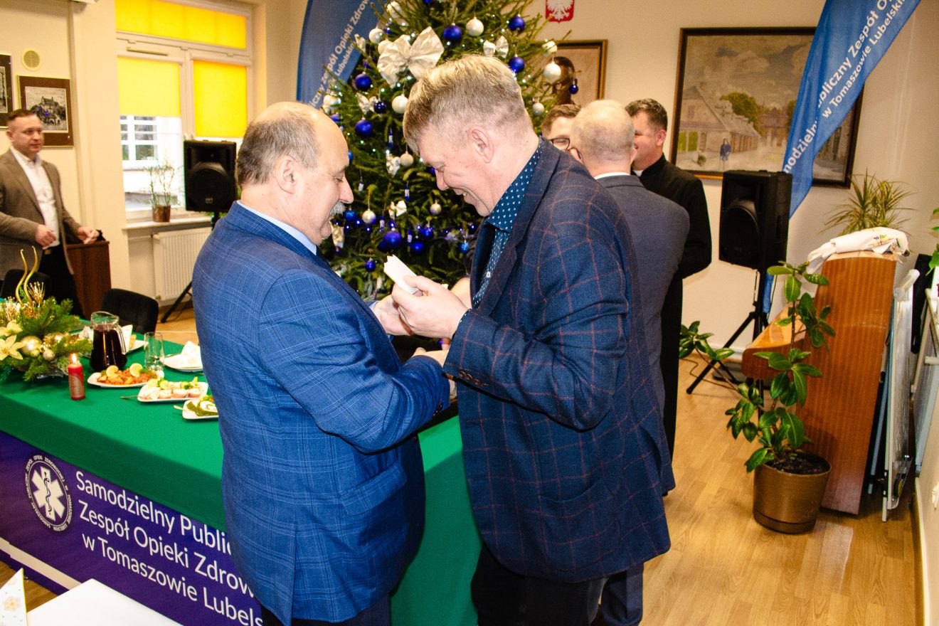 Członek Zarządu Powiatu dzieli się opłatkiem z uczestnikami spotkania w SP ZOZ w Tomaszowie Lubelskim.