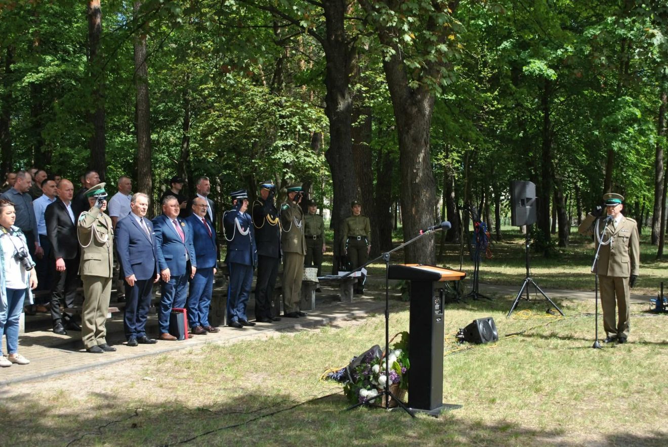 Uczestnicy obchodów Święta Straży Granicznej stoją podczas uroczystego apelu w parku w Lubyczy Królewskiej.