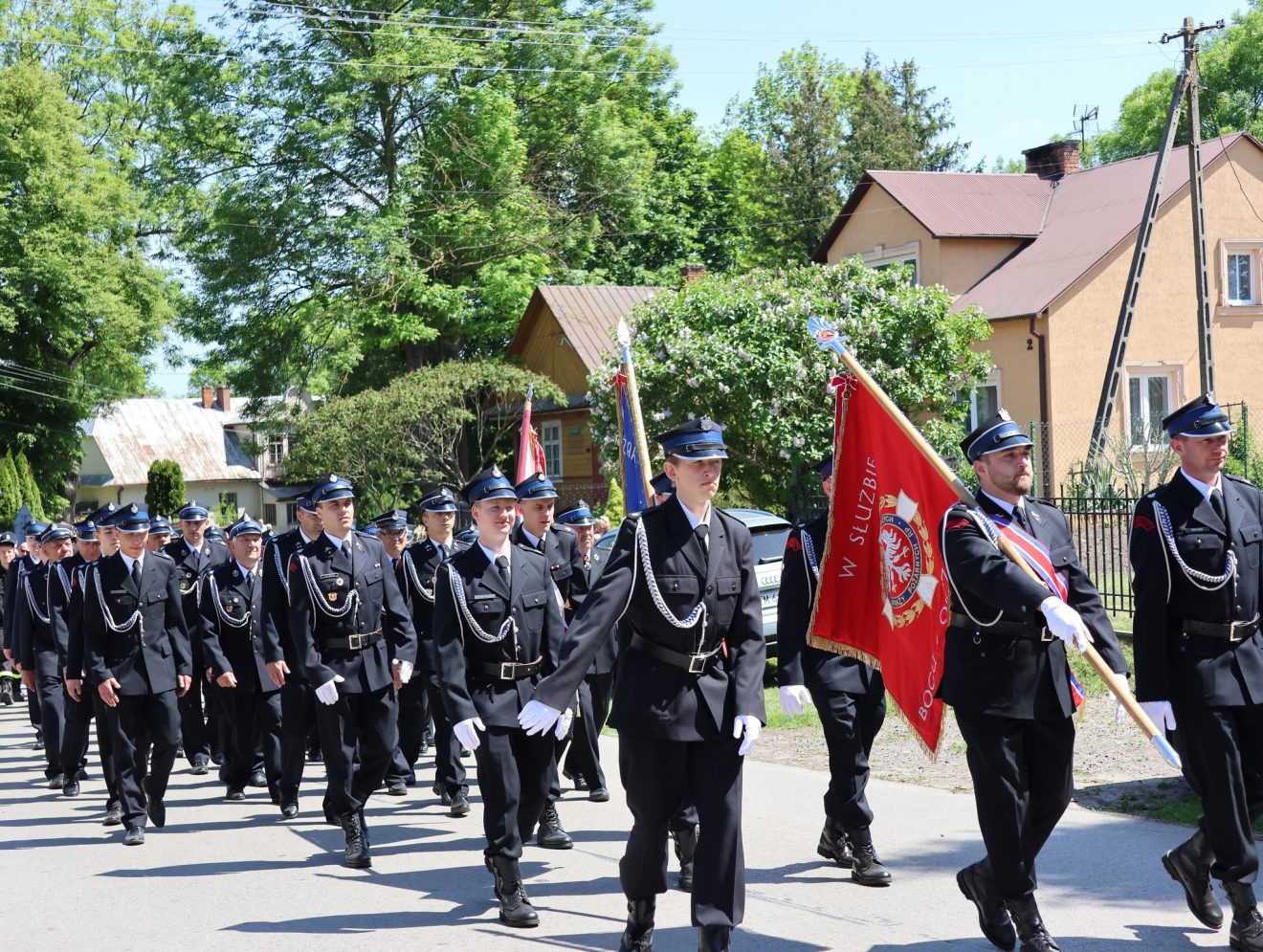 Strażacy maszerują ulicą podczas uroczystego przemarszu w Gródku.