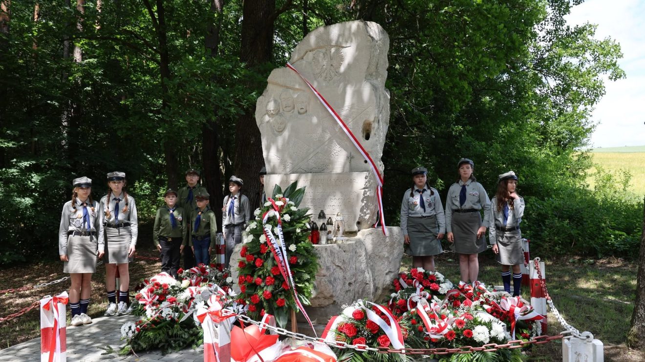Harcerze pełnią wartę honorową przy pomniku upamiętniającym ofiary zbrodni.