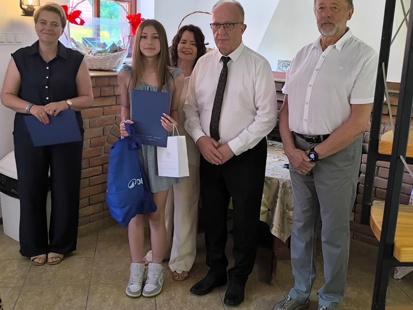 Na zdjęciu znajdują się Starosta Tomaszowski - Henryk Karwan oraz uczennica ze szkoły w Rachaniach oraz 3 inne osoby.