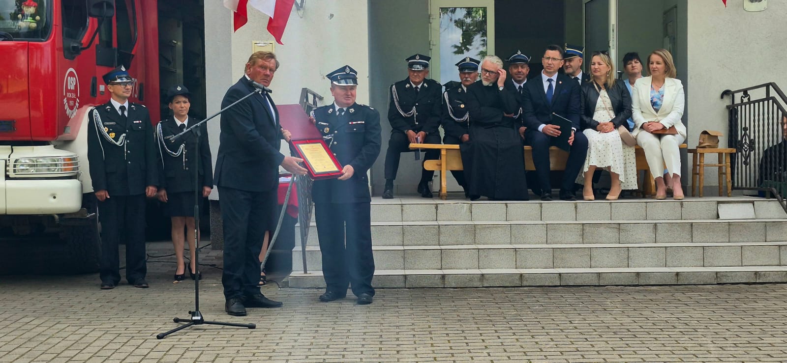 Przedstawiciel Powiatu Tomaszowskiego wręcza pamiątkowy grawerton podczas obchodów 75-lecia OSP Nowosiółki.