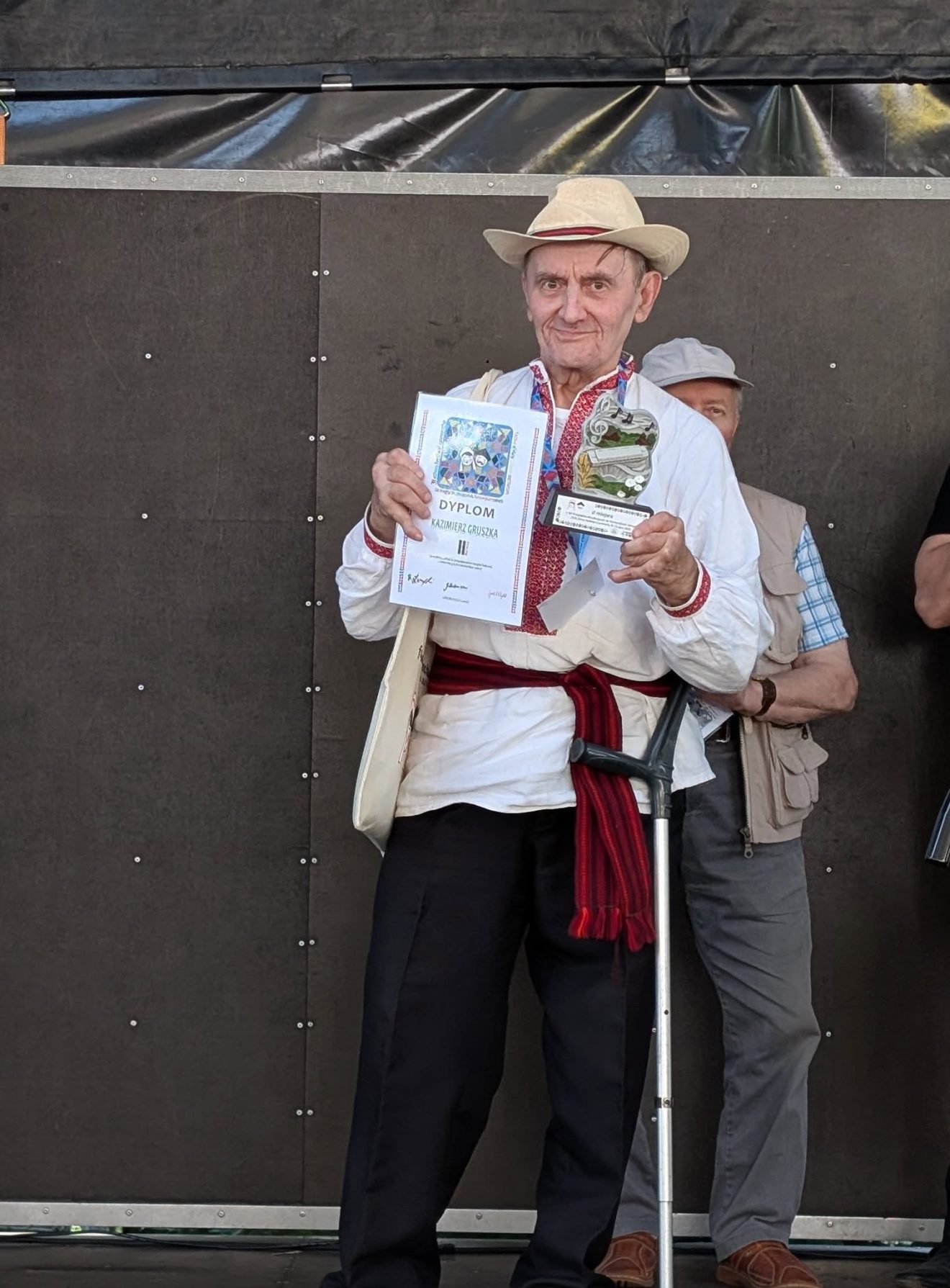 Kazimierz Gruszka prezentuje dyplom za II miejsce oraz pamiątkową statuetkę na scenie.