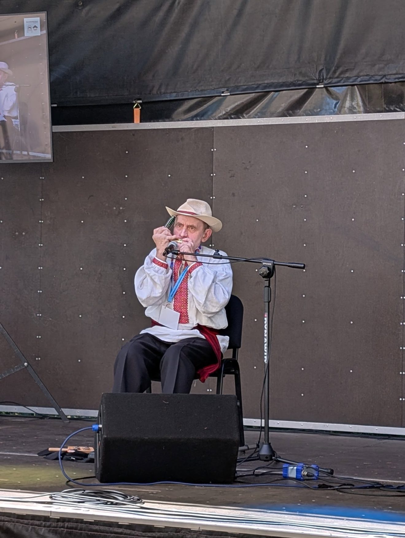 Kazimierz Gruszka podczas występu gra na harmonijce ustnej na festiwalowej scenie.
