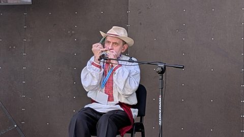 Kazimierz Gruszka podczas występu gra na harmonijce ustnej na festiwalowej scenie.