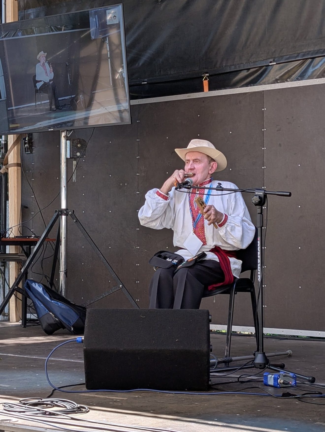 Kazimierz Gruszka podczas występu gra na harmonijce ustnej na festiwalowej scenie.