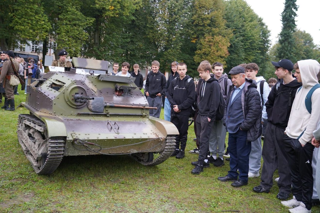 Czołg z okresu II wojny światowej i młodzież uczestnicząca w wydarzeniu historycznym.